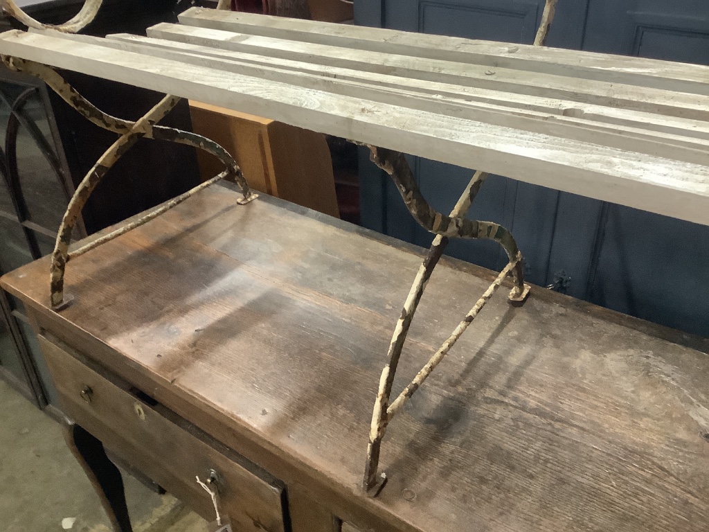 A white painted wrought iron garden seat with wooden slatted seat, width 121cm